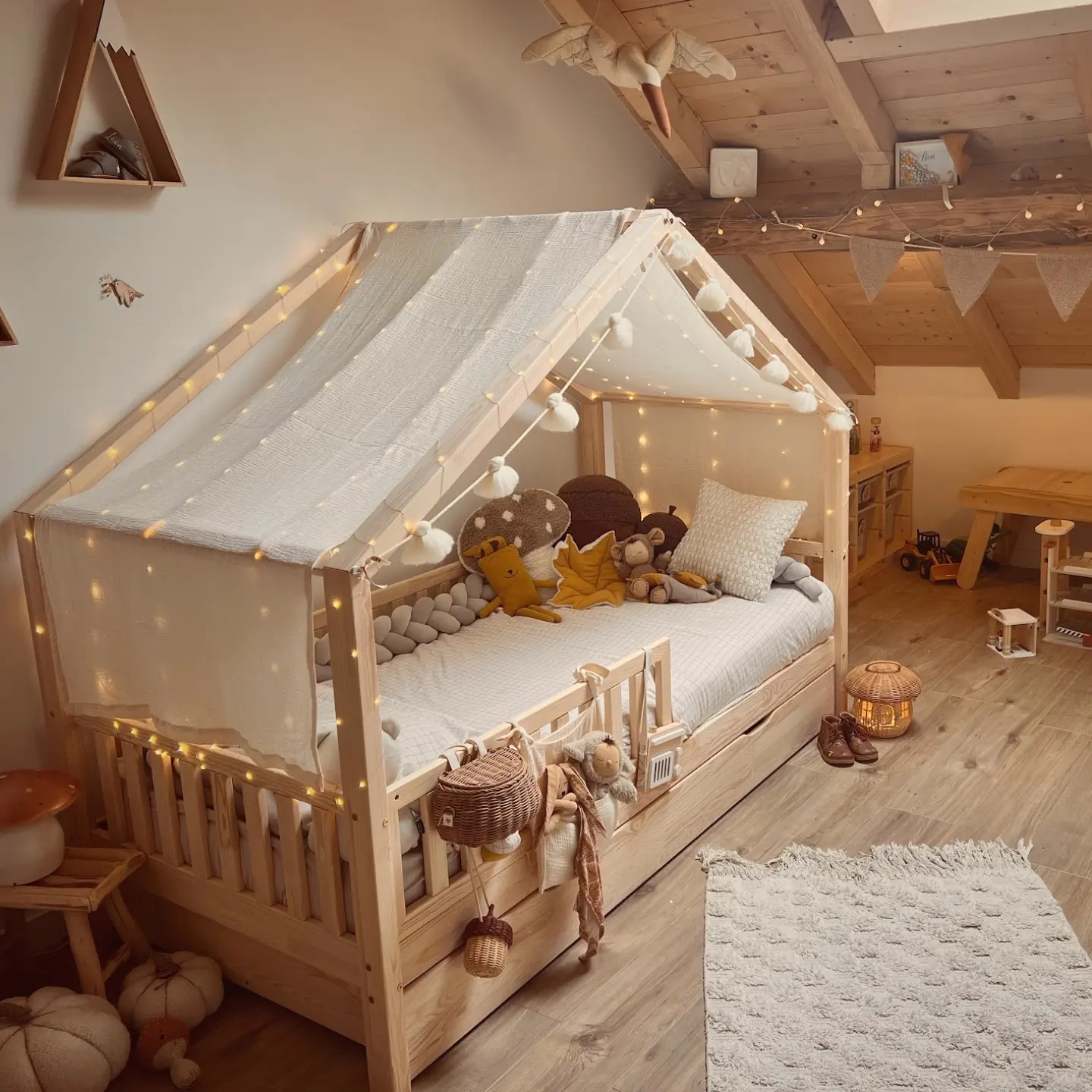 Lit Montessori en bois naturel avec décoration de guirlande lumineuse dans une chambre d'enfant chaleureuse