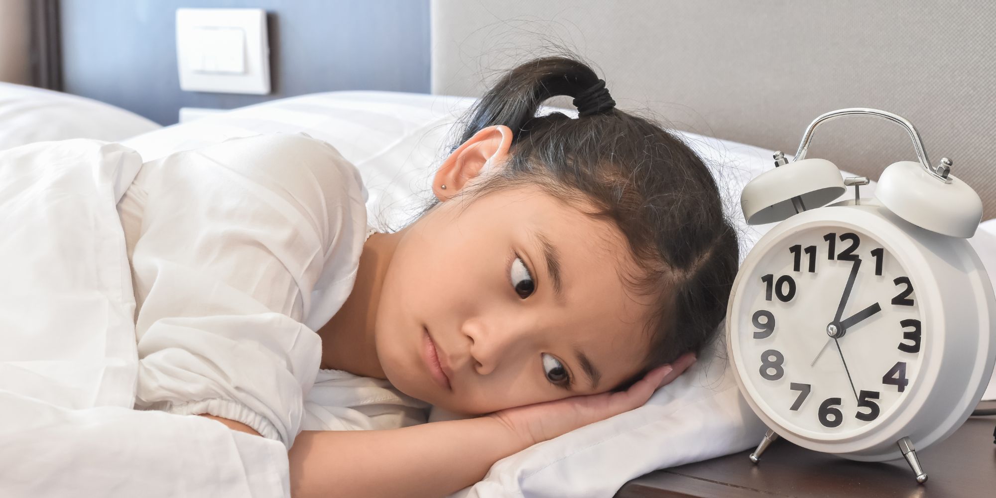 Enfant inquiet regardant un réveil, montrant les effets du manque de sommeil et de l'insomnie.