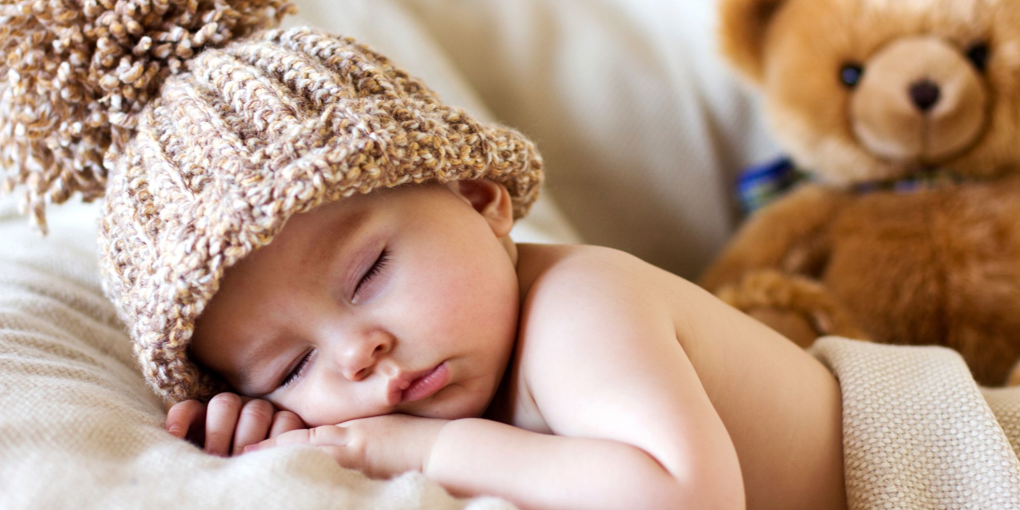 Nourrisson endormi avec un chapeau en tricot, illustrant un sommeil profond et réparateur.