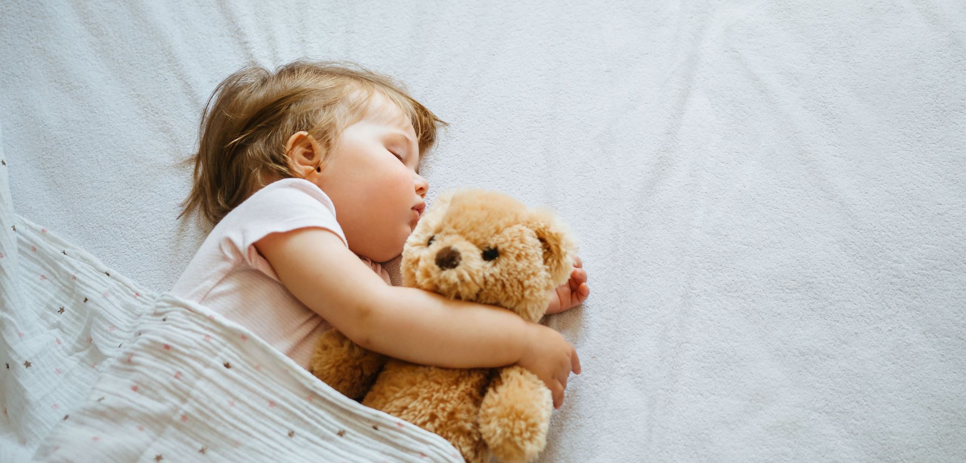 Enfant endormi sous une couette, marquant la transition de la gigoteuse